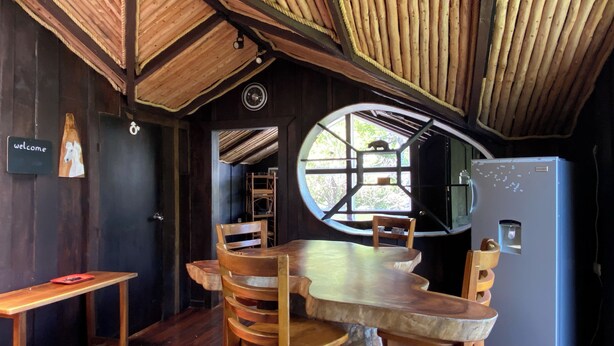 A rustic wooden interior with a round window, a wooden table, and chairs. - TreeTop House Getaway, Fairy Magic Rustic Elegance in the Cloud Forest, 3 Levels (Monteverde)