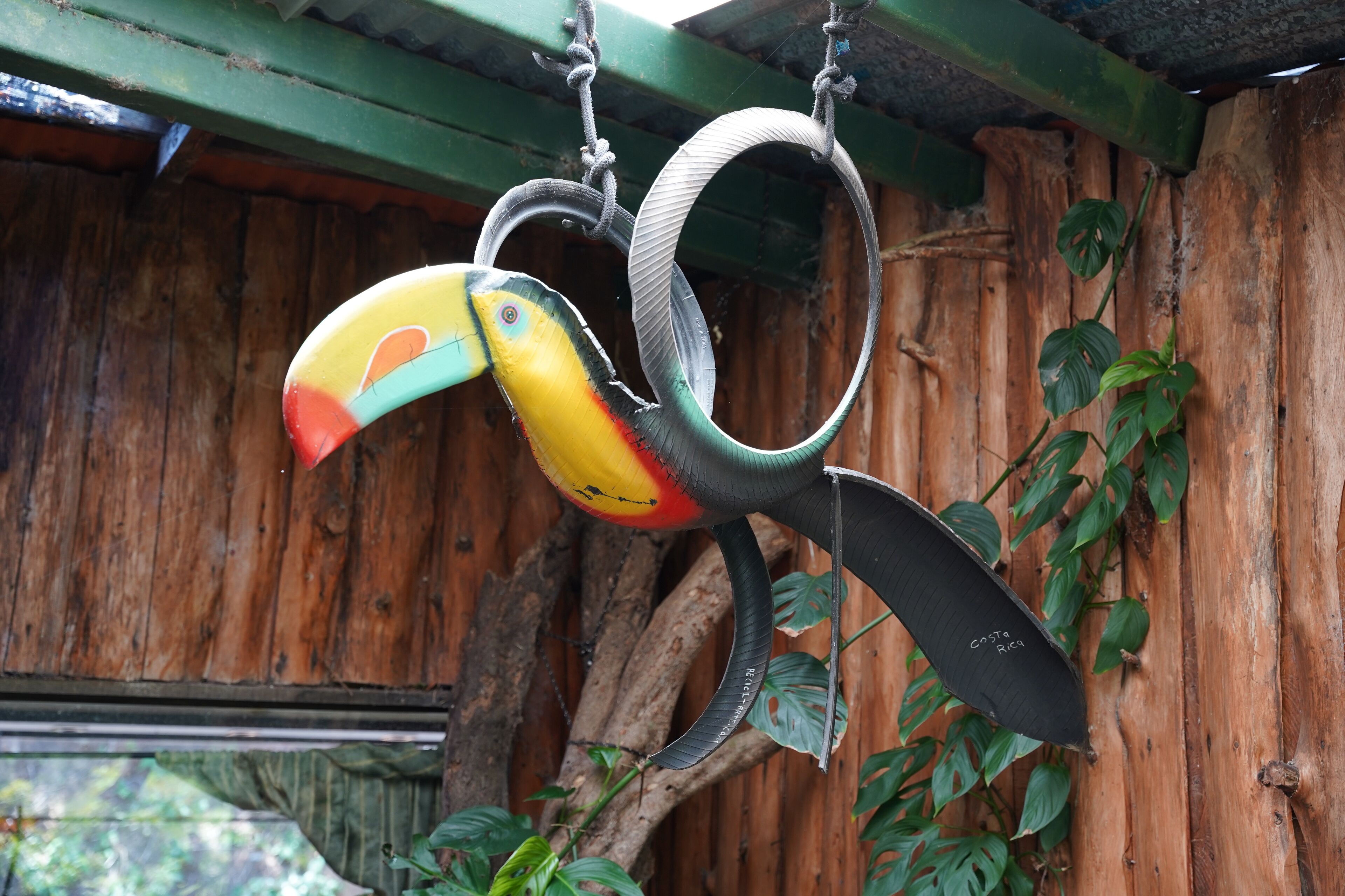 A birdcage with a wooden exterior and a hanging hook.
