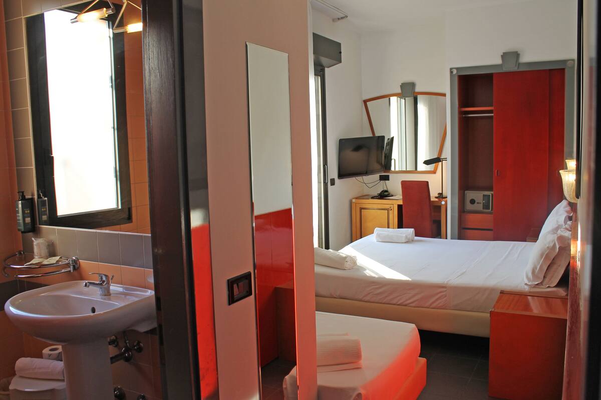 Une chambre d’hôtel avec salle de bain, un lit, une télévision et une armoire.