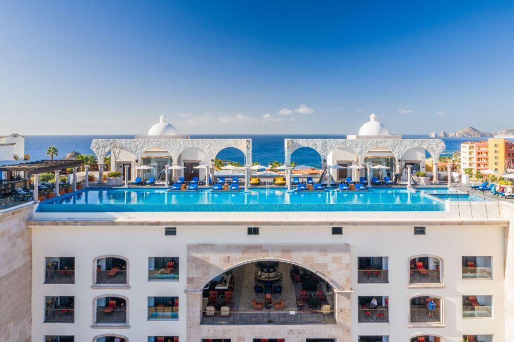 A hotel with a rooftop pool, multiple balconies, and a view of the sea.