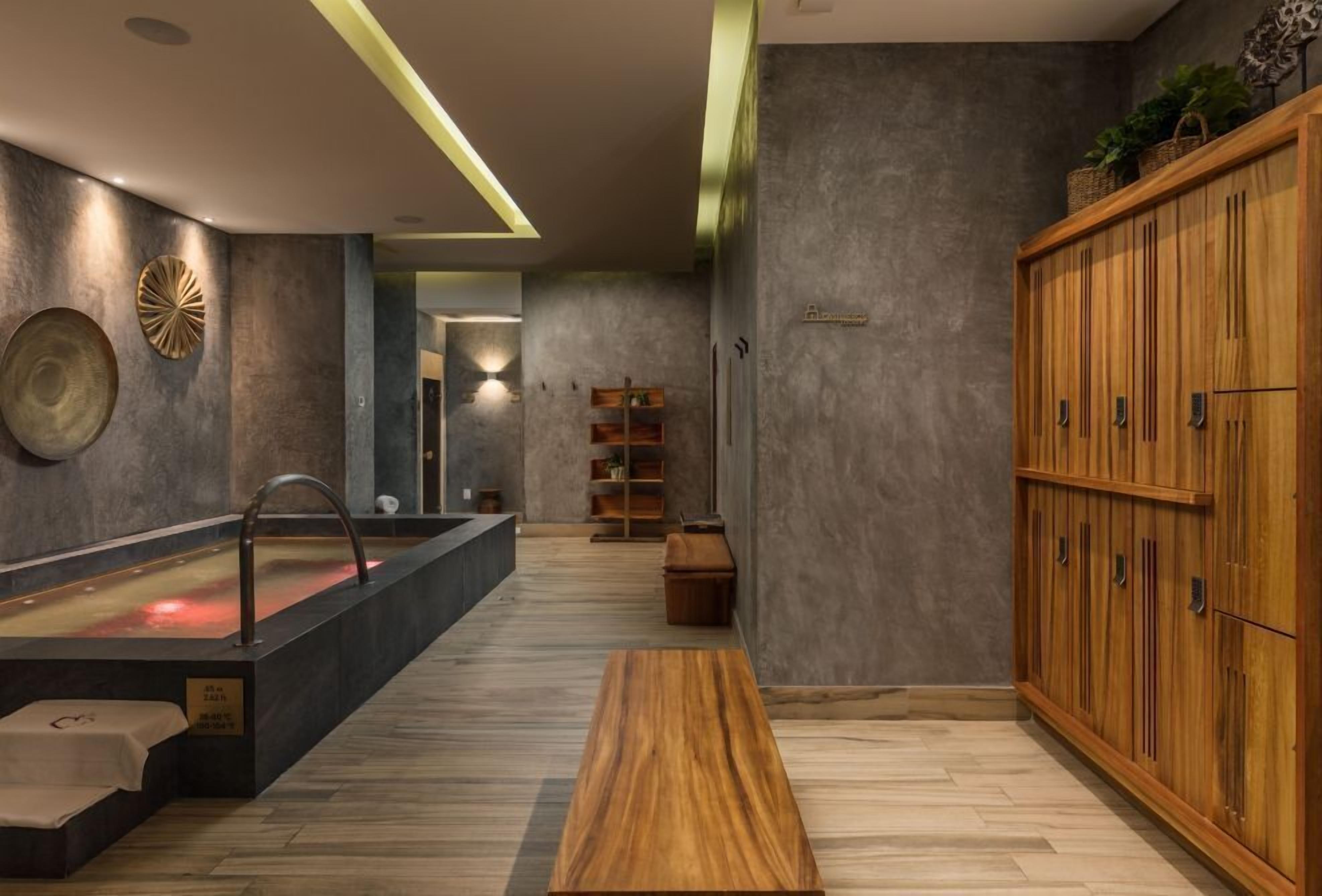 A modern spa area with a heated stone bath, wooden benches, and a large wooden cabinet.