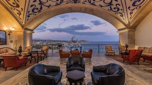 Una terrazza con vista sul mare, arredata con divani e poltrone in pelle e un soffitto decorato.