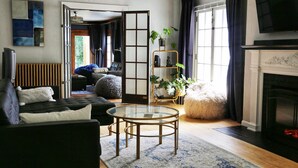 A modern living room with a sofa, a glass coffee table, a fireplace, and a large window with curtains. - Riverfront Getaway (Two Rivers)