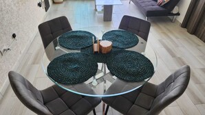 Una mesa redonda de vidrio con cuatro individuales oscuros tejidos y un centro de madera.