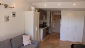 A modern living room with a grey sofa, a small table, and a wardrobe. - Nice studio with terrace port de hyeres (Hyères)