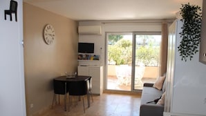 A compact living space with a dining area, a sofa, and a TV. - Nice studio with terrace port de hyeres (Hyères)