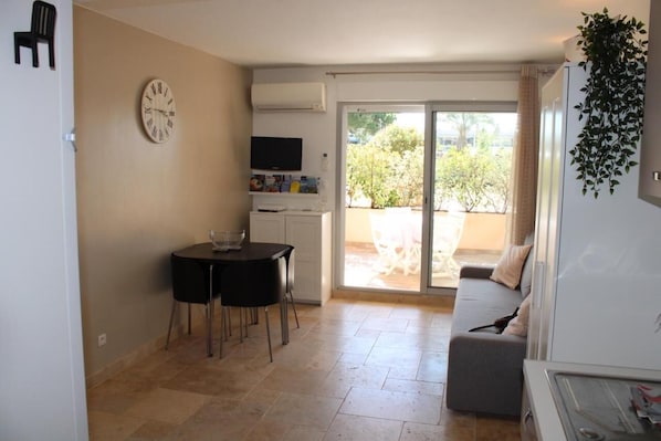 A compact living space with a dining area, a sofa, and a TV.