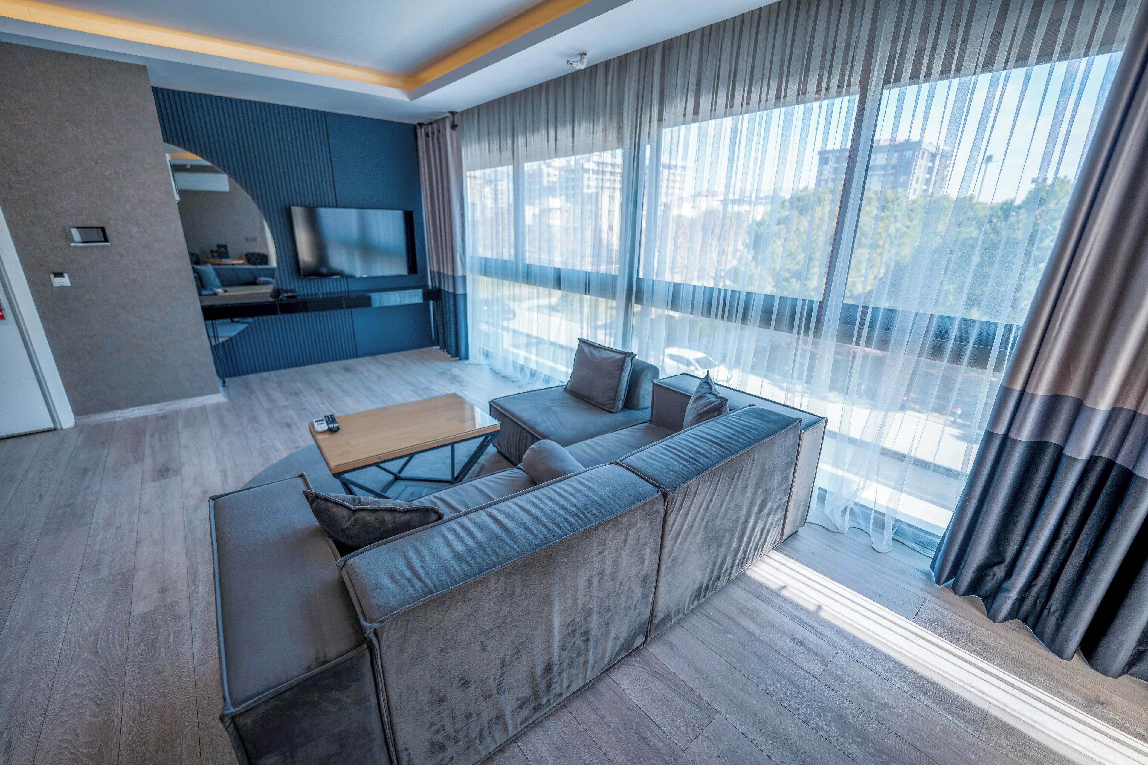 A modern living room with a grey sofa, a wooden coffee table, and a TV mounted on the wall.