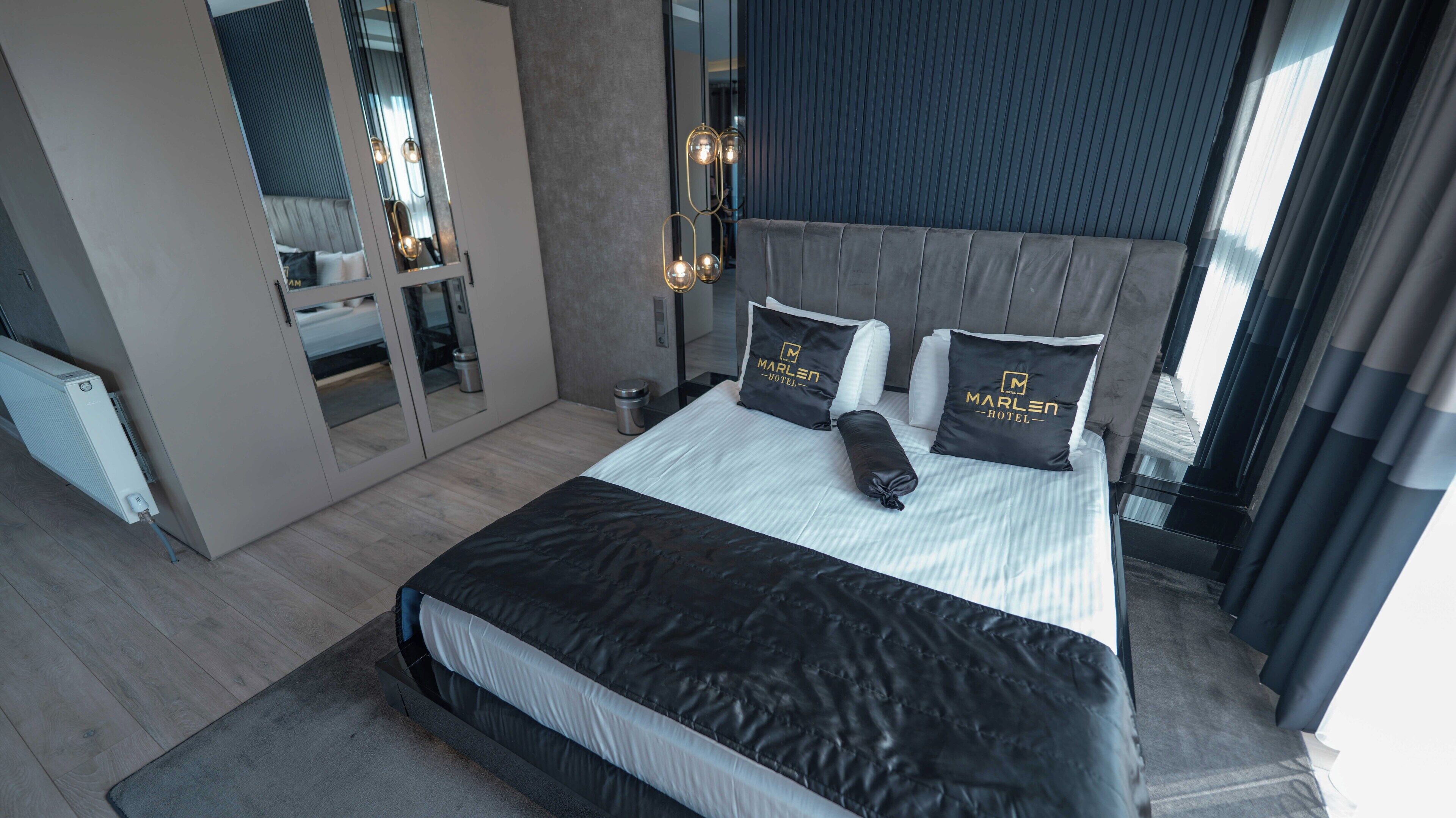 Una habitación de hotel moderna con una cama grande, una mesita de noche, un espejo y vistas de la ciudad.