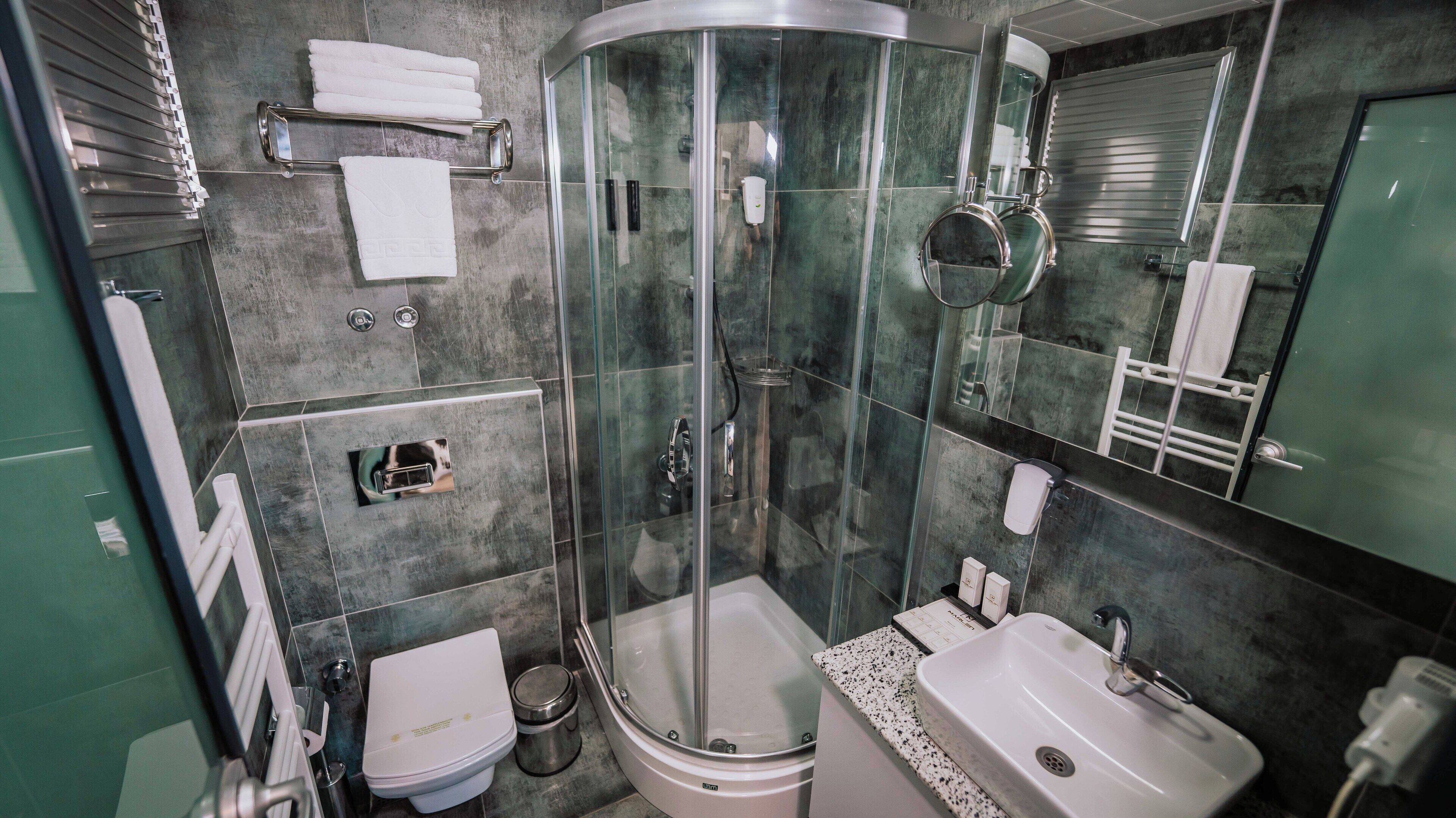A modern bathroom with a glass-enclosed shower, a toilet, a sink, and a towel rack.