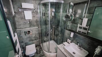 A modern bathroom with a glass-enclosed shower, a toilet, a sink, and a towel rack.