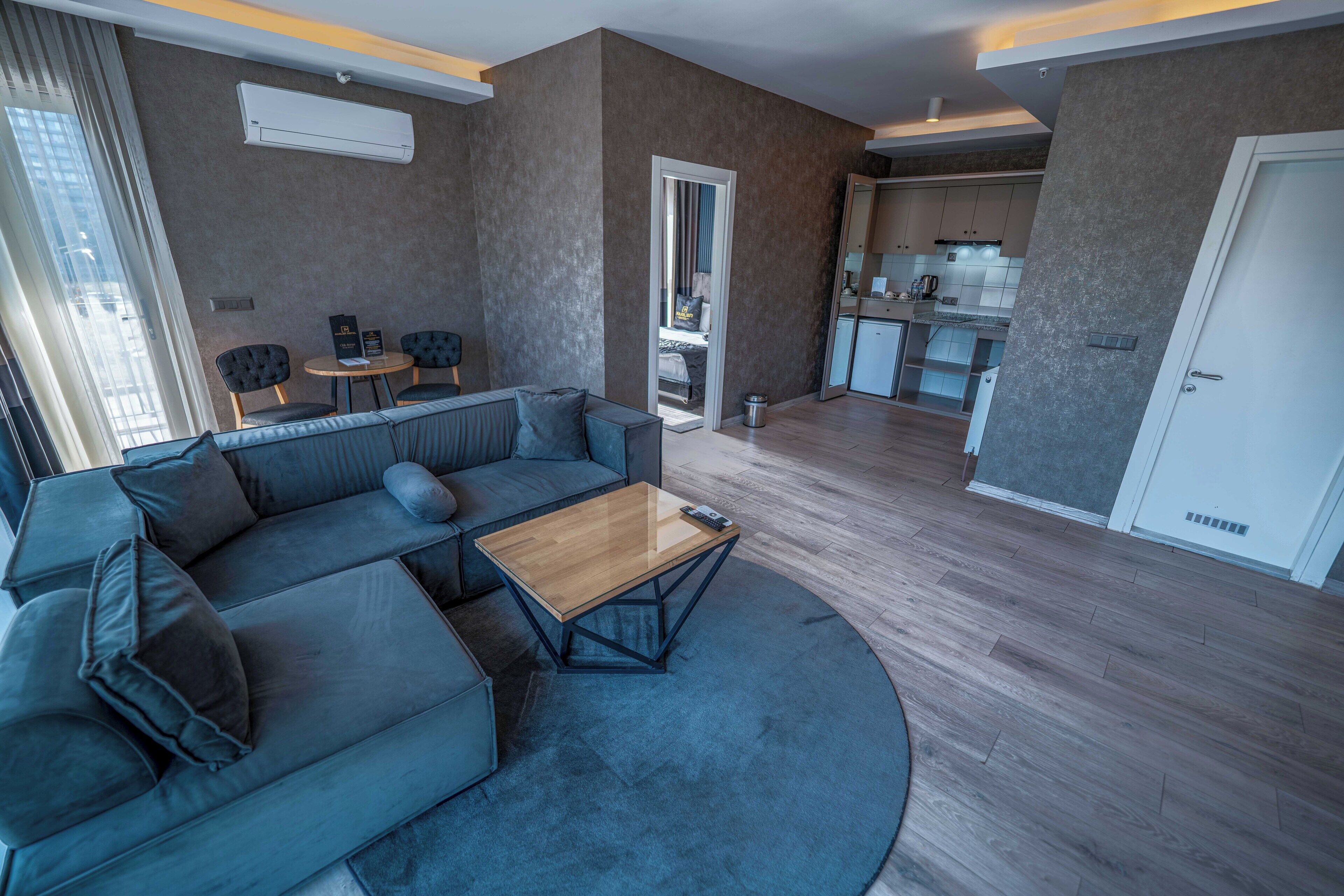 A modern living room with a sectional sofa, a coffee table, and a dining area with a kitchen in the background.