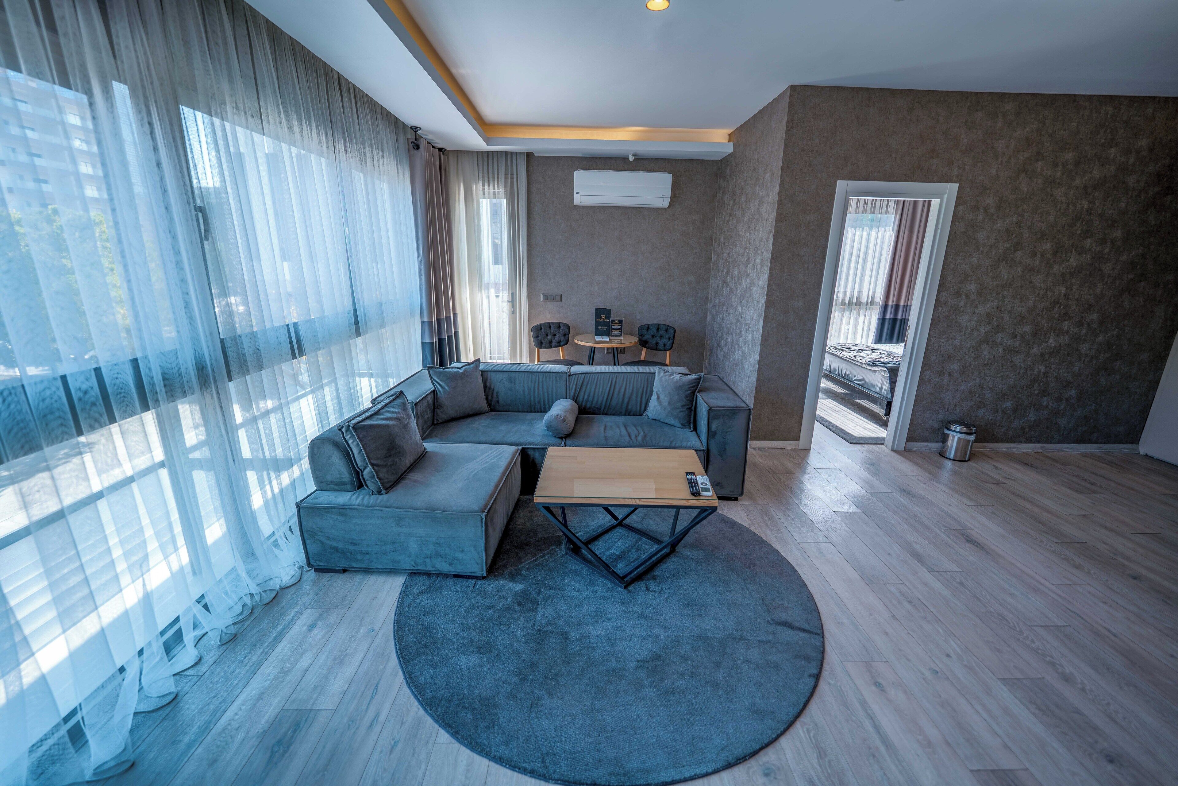 Una sala de estar moderna con un sofá seccional, una mesa de centro redonda y una zona de comedor con dos sillas.