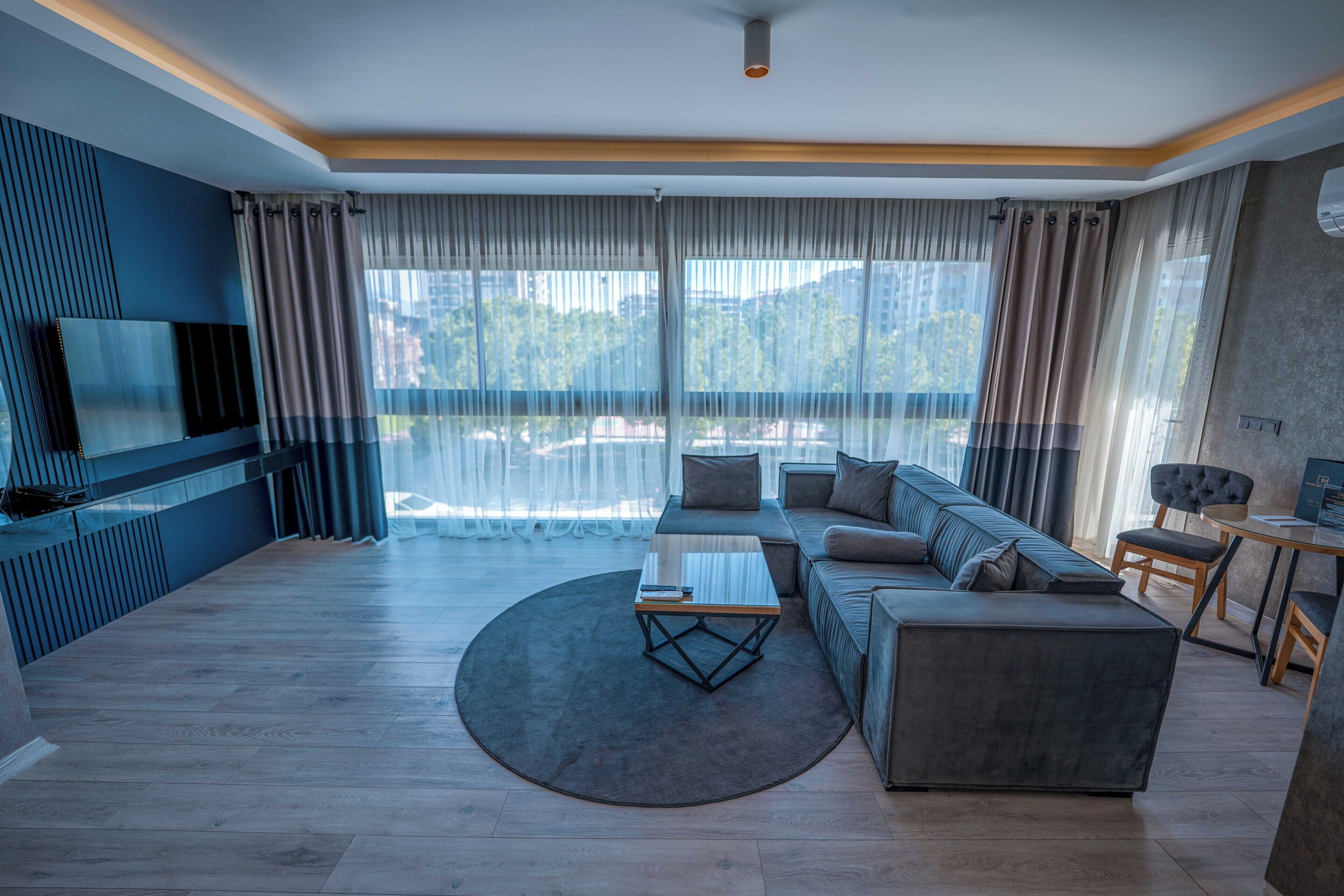 A modern living room with a sectional sofa, a coffee table, and a flat-screen TV mounted on the wall.
