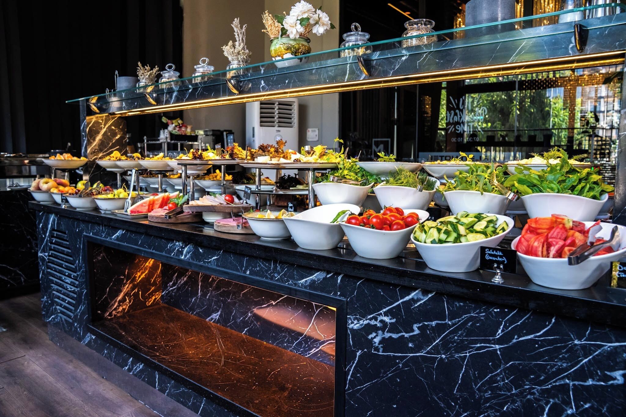 A buffet with various food items and a marble countertop.