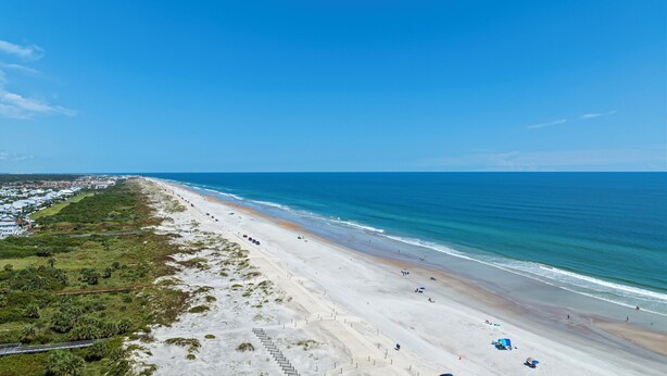 A beach with a long stretch of sandy shore, a clear blue sky, and a view of the ocean. - Oceanfront St Augustine Beach Condo/ Steps to Pool +  Beach (St. Augustine Beach)