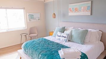 A bedroom with a bed, a chair, a nightstand, and a window with blinds.