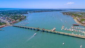 An aerial view of a coastal town with a prominent bridge connecting two areas, numerous boats docked at a marina, and a clear view of the surrounding landscape. - Oceanfront St Augustine Beach Condo/ Steps to Pool +  Beach (St. Augustine Beach)