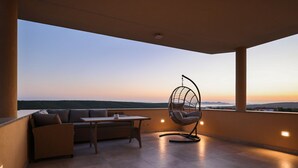 A balcony with a hanging chair, a sofa, and a table, overlooking a scenic landscape during sunset. - Villa Morella with Heated Pool (Sukošan)