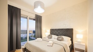 A bedroom with a large bed, two bedside tables with lamps, a view of the outdoors through a window, and a ceiling light. - Villa Morella with Heated Pool (Sukošan)