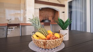 A table with a fruit basket containing pineapple, bananas, grapes, and oranges. - Villa Morella with Heated Pool (Sukošan)