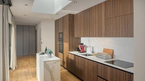 Een moderne keuken met houten kastjes, een marmeren aanrechtblad en een ingebouwde oven.