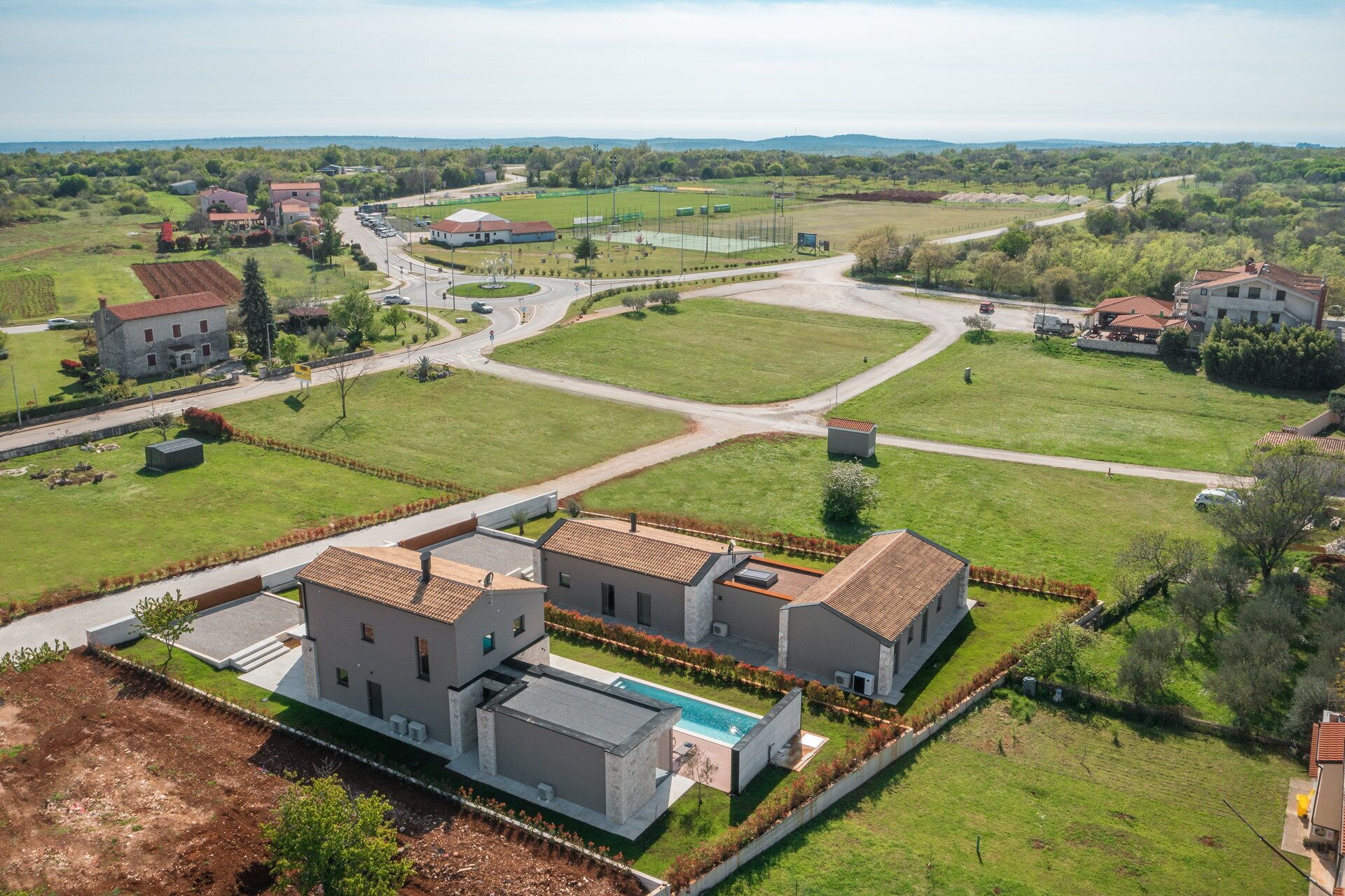 A residential area with modern houses, a swimming pool, and a well-maintained lawn.