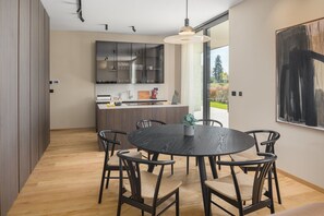 Une cuisine moderne avec des meubles de couleur sombre, un îlot central et un coin repas comprenant une table ronde et des chaises.