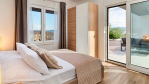 Un dormitorio con cama, vistas al exterior y un ventanal corredero que da a una zona de estar al aire libre.