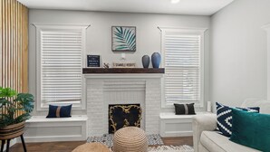 A living room with a fireplace, white walls, and a sofa. - Tampa Stylish Bungalow Oasis (Tampa)