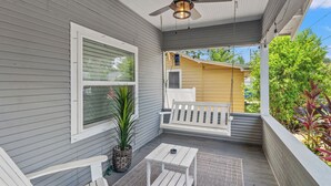 A covered porch with a ceiling fan, a white bench, a small table, and a potted plant. - Tampa Stylish Bungalow Oasis (Tampa)