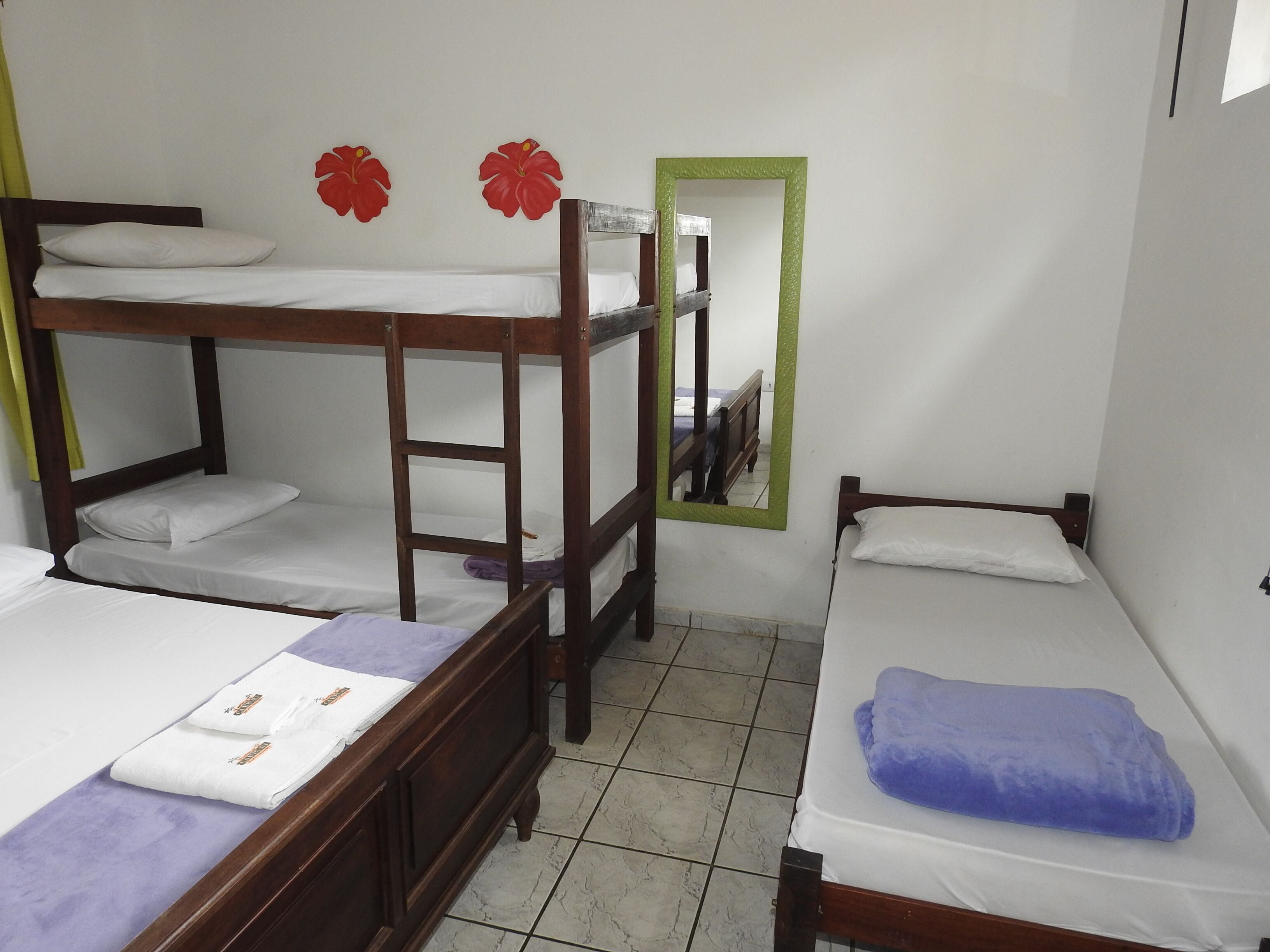 A dormitory room with bunk beds, a mirror, and a small window.