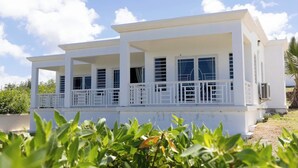 A white two-story building with multiple balconies and large windows.