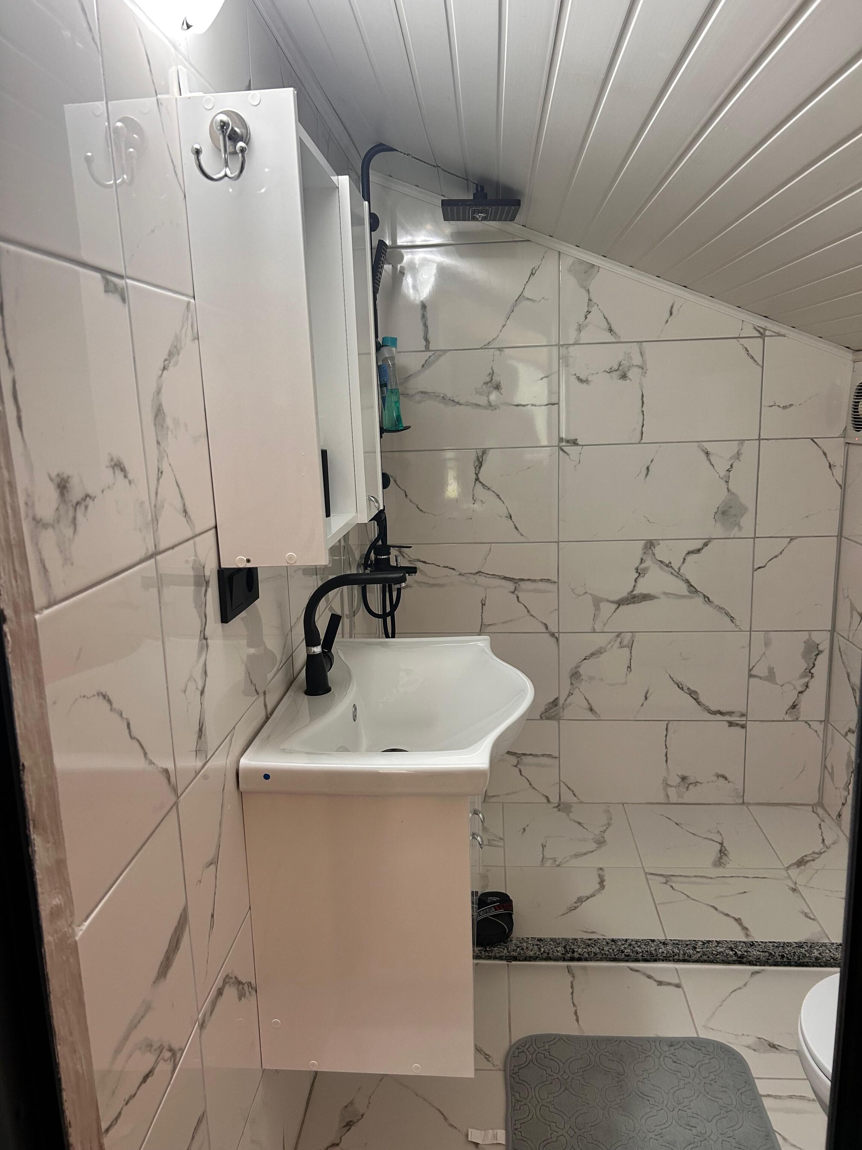 A bathroom with a white sink, a mirror, and a shower area.