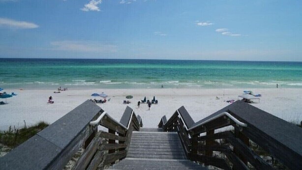 A beach with a wooden staircase leading to the shore, clear blue water, and a few beach umbrellas. - Golf Cart & Pool included! Pet-Friendly Retreat <1 mile from Beach (Santa Rosa Beach)
