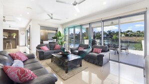 A modern living room with a sofa set, a coffee table, and a view of a body of water through large glass doors. - Zen Bayview Bliss: Luxury Marina Mansion (Bayview)