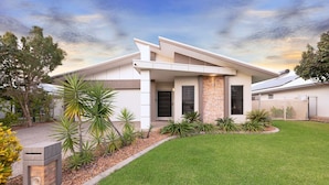 A modern two-story house with a flat roof, a front porch, and a well-maintained lawn. - Zenhouse Stylish: Lawn ~ Workspace ~ OutdoorDining (Muirhead)