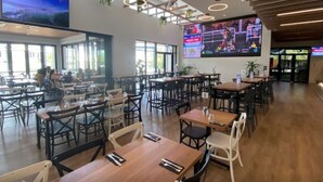 A spacious restaurant with high ceilings, large windows, and a variety of seating arrangements including tables and chairs. - Zenhouse Stylish: Lawn ~ Workspace ~ OutdoorDining (Muirhead)