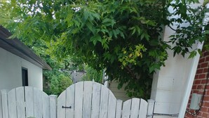 Un cancello con un vialetto in cemento che conduce a un piccolo giardino con rocce e piante.
