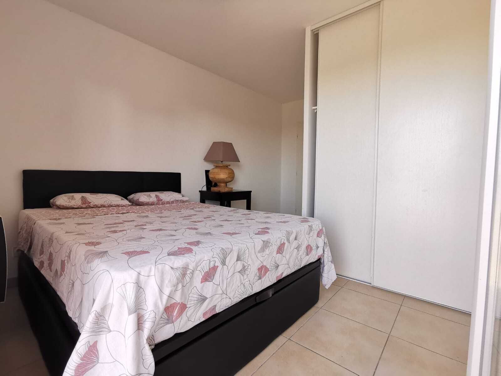 Ein Schlafzimmer mit Bett, Nachttisch, Lampe und Kleiderschrank.
