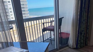 Ein Zimmer mit Blick auf den Strand, inklusive Tisch, Stuhl und einer Schiebetür.