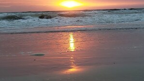Ein Strand mit Wellen und einem Sonnenuntergang.