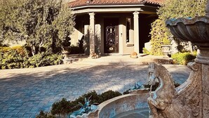Ein großes, beeindruckendes Gebäude mit einem markanten Eingang, einem Brunnen und einem gepflegten Garten.