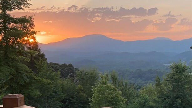 A wooden deck with a view of a mountainous landscape during sunset. - Windrock Cabin On The Hill (oak ridge)
