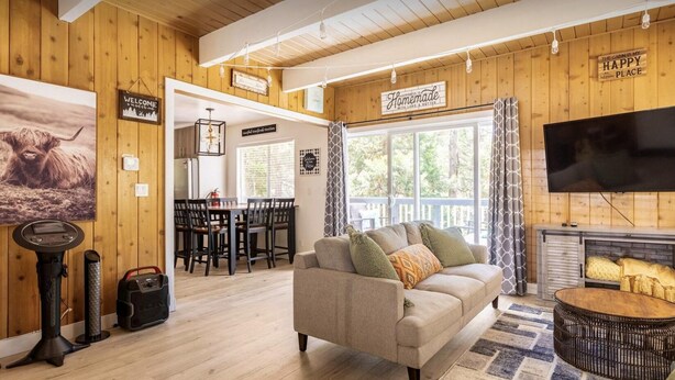 A cozy cabin interior with a wooden interior, a dining area, a sofa, and a TV. - Arrowhead cabin sleeps 12 fast wifi newly remodeled (Lake Arrowhead)