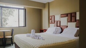 Une chambre d’hôtel avec un grand lit, une petite table et une chaise.