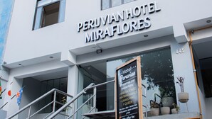 La façade de l’hôtel péruvien Miraflores, avec une enseigne indiquant les services proposés et un escalier menant à l’entrée.