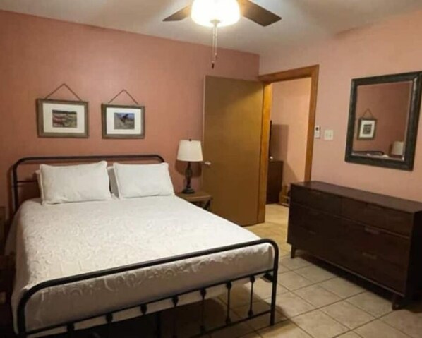 A bedroom with a bed, a dresser, a ceiling fan, and two framed pictures on the wall. - Peek-a-Moo Apt w/patio, paddle boating (Raymondville)