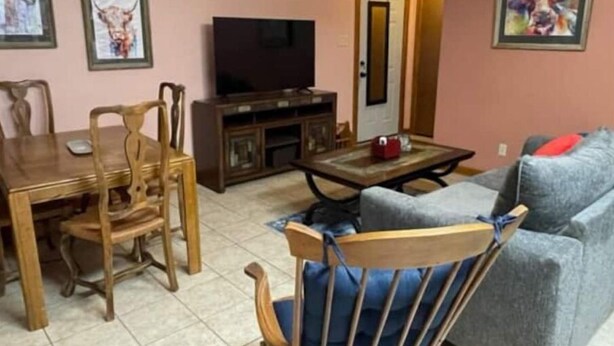 A living room with a dining table, chairs, a sofa, a TV, and artwork on the walls. - Peek-a-Moo Apt w/patio, paddle boating (Raymondville)
