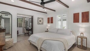 Une chambre à coucher avec un grand lit, un ventilateur de plafond, un bureau et une chaise.